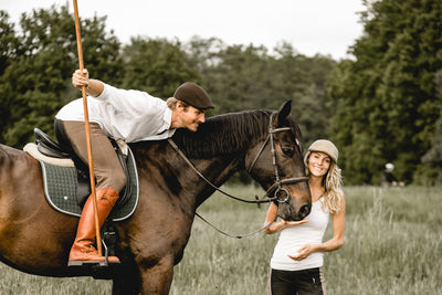 Working Equitation Outfit: Braunes Pferd mit Reiter im Working Equitation Stil mit Polostiefel und Vaquera Mütze